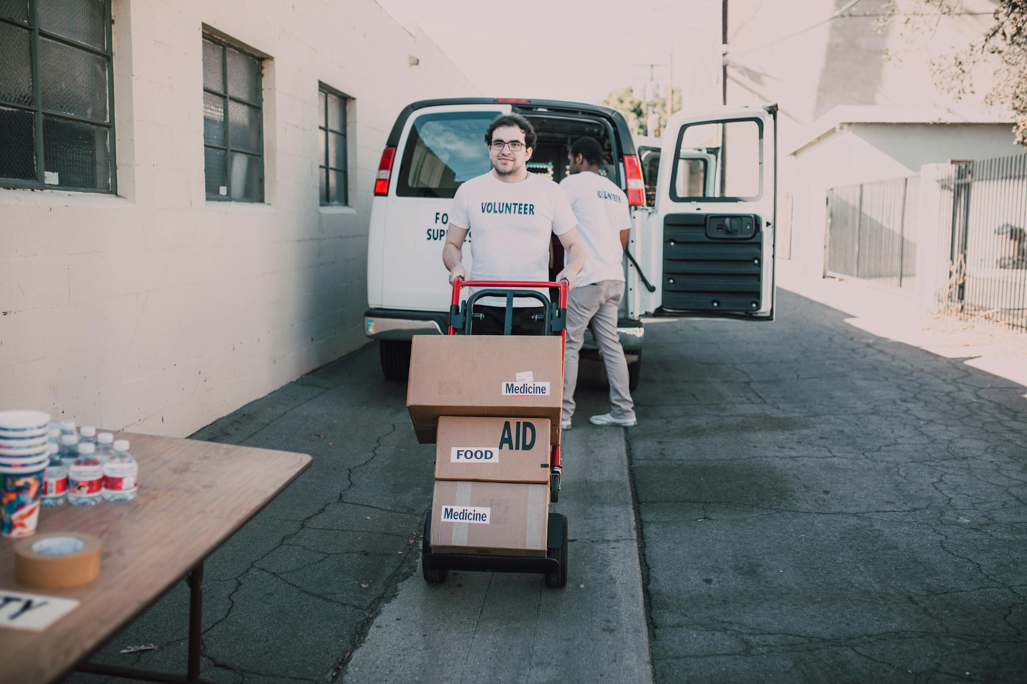 Volunteers unloading aid boxes with essential supplies like food and medicine.